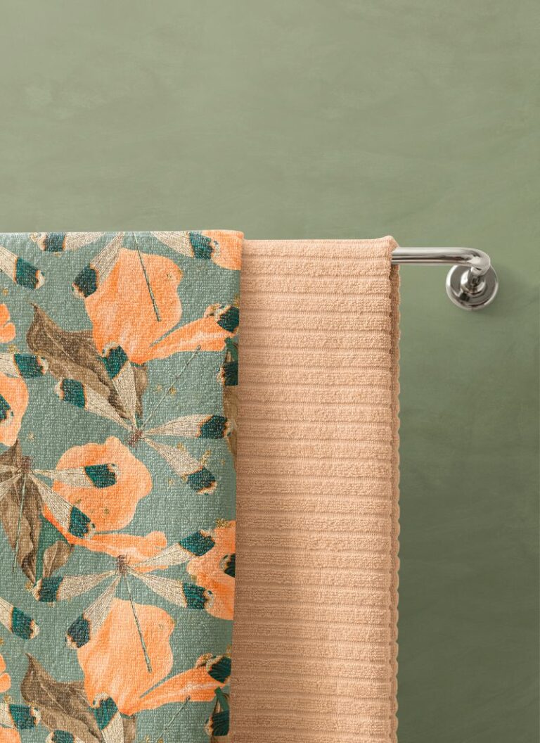 Two bath towels hanging against a grey-green wall